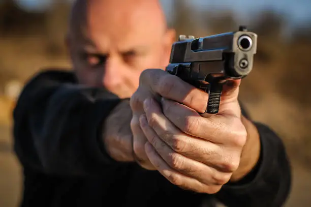 Police agent and bodyguard pointing pistol to protect from attacker. Gun point aiming front view outdoor