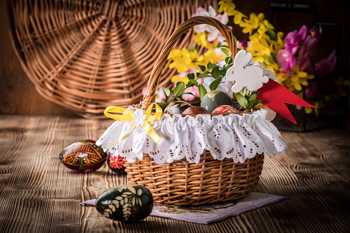 Traditional Easter basket with colored eggs on the wooden table.