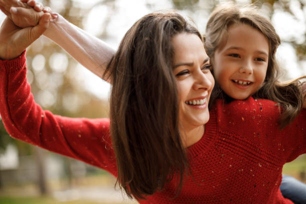 istock Happy mother carrying daughter piggyback 1085751044