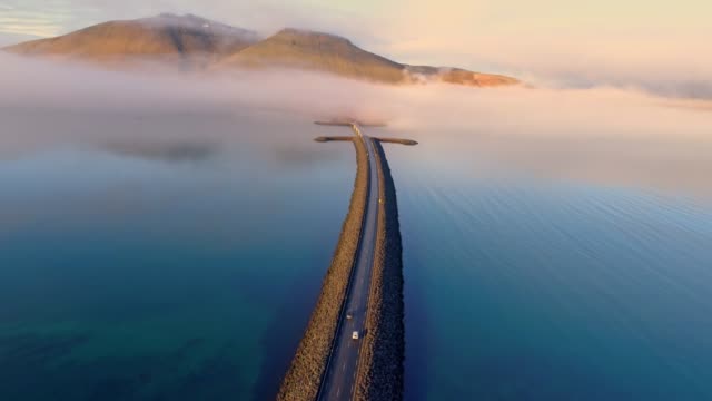 WS Aerial view car moving along road over remote mountain lake,Iceland