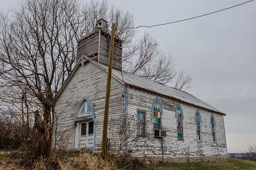 Looking up at a vintage rural church on a hill with an overcast day