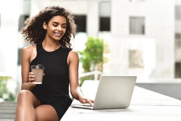 Photo of Smiling young mixed race woman using her laptop to chat online.