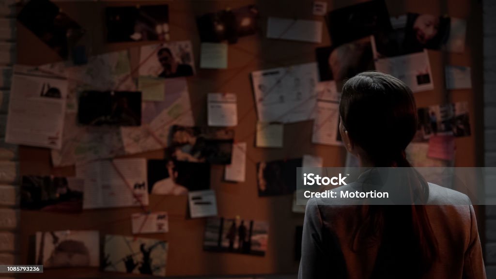 Lady private agent looking at crime investigation board, chasing serial killer Detective Stock Photo