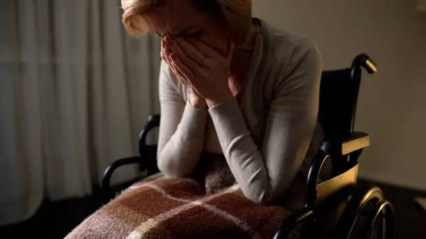 Sick woman wheelchair feeling lonely and depressed, hopelessness in nursing home