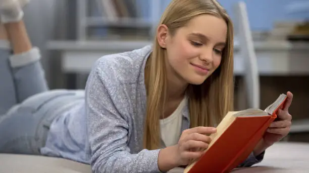 Photo of Teenage girl reading book, dreaming of romantic love, imagining heroic man