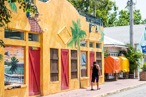 Key West, USA - May 1, 2018: Colorful red, orange, yellow building architecture of Blue Macaw restaurant, bar, cafe in Florida keys on sunny day, man, person, people walking on sidewalk