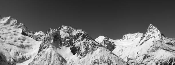 istock Black and white panorama of snowy covered mountain peaks 1085802982
