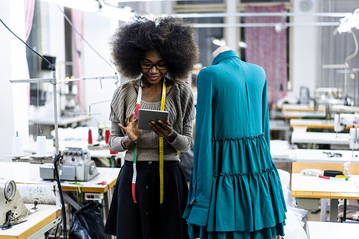 Female designer with tape measure working in fashion studio.