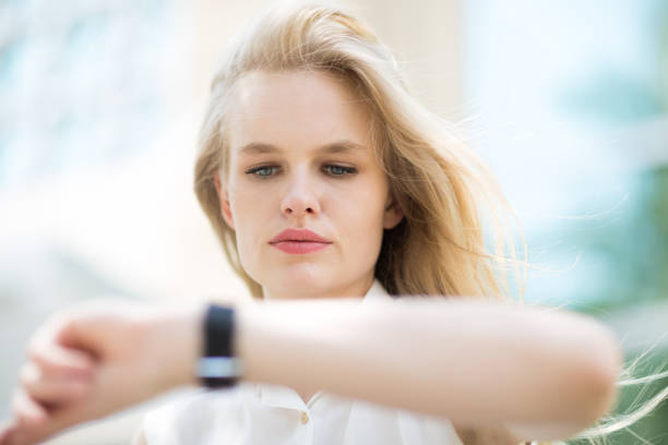 молодая бизнес-женщина проверяет время на своих часах. - checking the time women impatient wristwatch стоковые фото и изображения