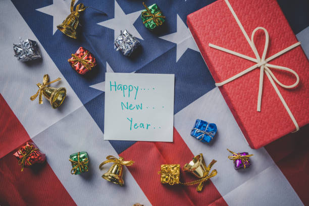 istock Christmas and New Year's Day, Top view holding hand note pad with message and Red gift box and ribbon with flag of the united states in the background. 1085805886