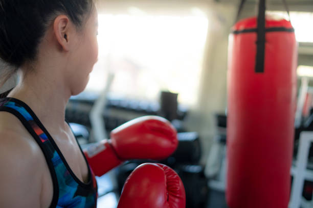 fitness-studio fitness- und trainingsgeräte und moderne kampfclub mit boxsäcke, boxing: bild von schnellen stanzen, boxsack von sport frauen boxen in box-gym trainieren. - fist women punching asian ethnicity stock-fotos und bilder