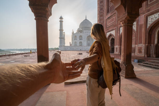 Couple holding hands at the Taj Mahal, India Follow me to the Taj Mahal, India. Female tourist leading boyfriend to there magnificent famous Mausoleum in Agra. People travel concept india indian culture taj mahal temple stock pictures, royalty-free photos & images