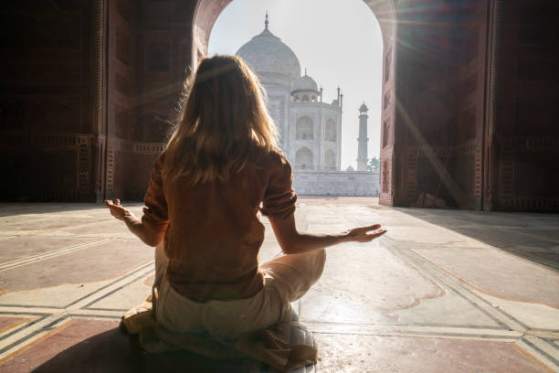 young woman practicing yoga in india at the famous taj mahal at sunrise -  people travel spirituality zen like concept - zen like nature breathing exercise sitting imagens e fotografias de stock