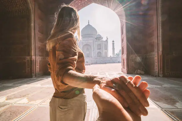 Follow me to the Taj Mahal, India. Female tourist leading boyfriend to there magnificent famous Mausoleum in Agra. People travel concept