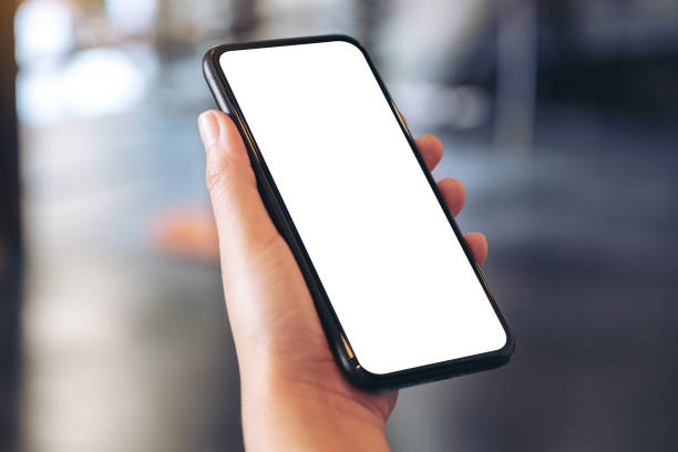 istock Mockup image of a hand holding black mobile phone with blank white desktop screen 1085855032
