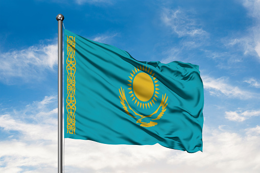 Flag of Kazakhstan waving in the wind against white cloudy blue sky. Kazakh flag.