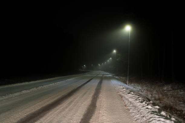 istock illuminated straight road with snow on it 1085877252