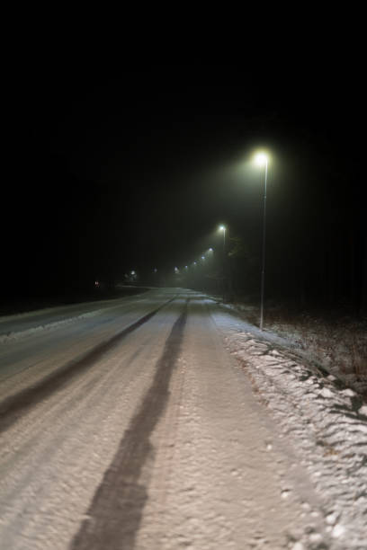 istock illuminated straight road with snow on it 1085877258