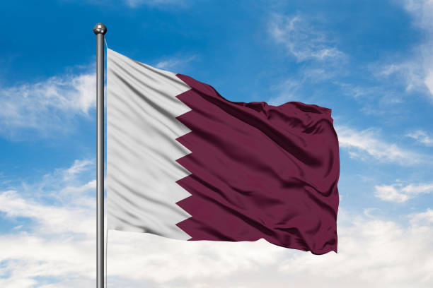 Flag of Qatar waving in the wind against white cloudy blue sky. Qatari flag. Flag of Qatar waving in the wind against white cloudy blue sky. Qatari flag. qatar flag stock pictures, royalty-free photos & images