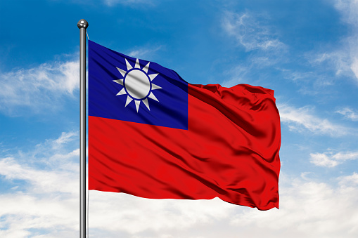 Flag of Taiwan waving in the wind against white cloudy blue sky. Taiwanese flag.
