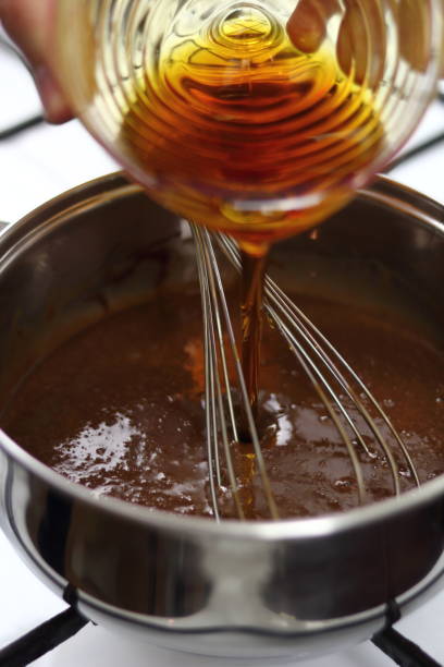 istock Pouring golden syrup into chocolate mixture. Making Chocolate, Pear and Pecan Pie Series. 1085912156