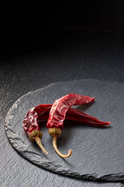 istock Closeup on two dry red chili peppers on slate stone background 1085915500