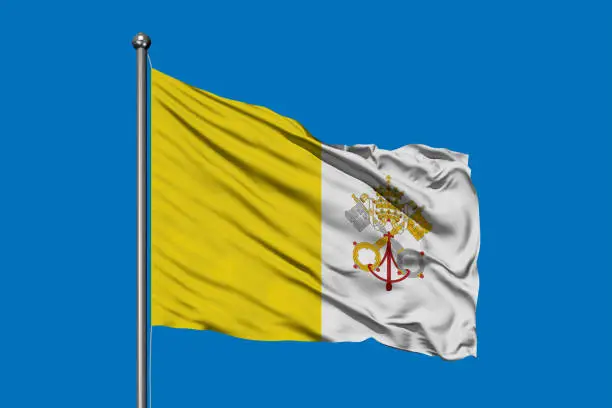 Flag of Vatican City waving in the wind against deep blue sky.