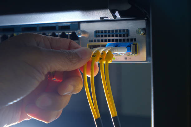 mano del ingeniero y fibra óptico cable del sistema conectado a red router switch en una sala de centro de datos de tecnología - high speed technology cable computer network fotografías e imágenes de stock