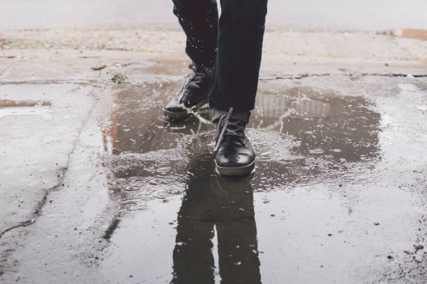 istock Male foot steps into puddle with large water splash 1085936338