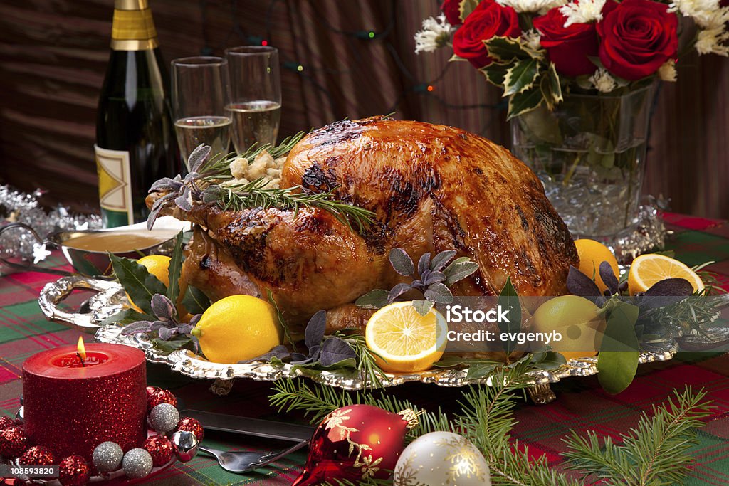 Christmas Feast Turkey Garnished roast turkey on Christmas-decorated table with candles and flutes of champagne. Roast Turkey Stock Photo