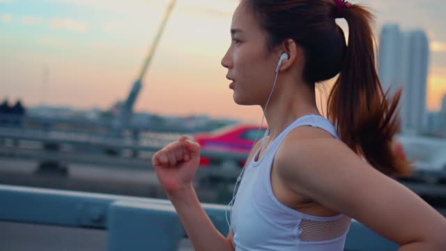 Slow motion of Young woman jogging across the bridge