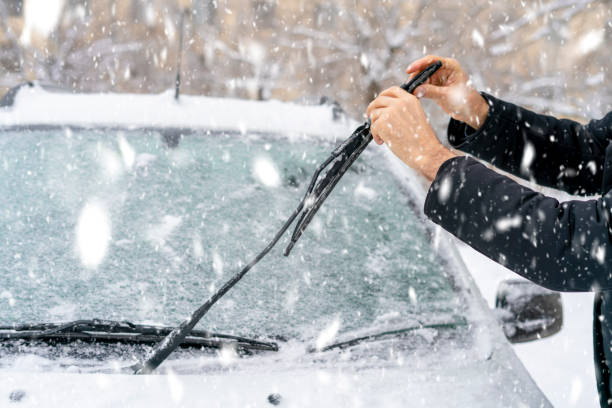 man adjusting and cleaning wipers of car in snowy weather b man adjusting and cleaning wipers of car in snowy weather car snow stock pictures, royalty-free photos & images