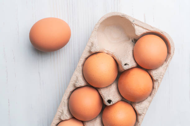 fresh eggs in paper tray on white surface b stock photo