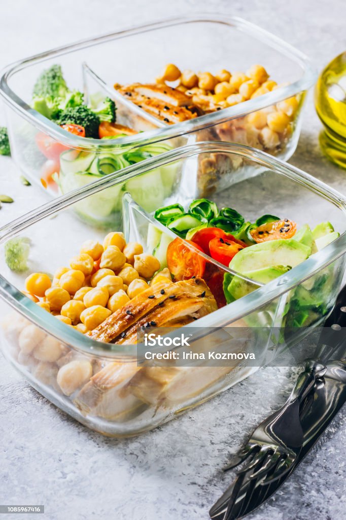 Healthy meal prep containers chicken and fresh vegetables. Healthy meal prep containers with chickpeas, chicken, tomatoes, cucumbers, avocados and broccoli. Top view Preparing Food Stock Photo