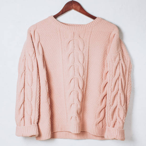istock Female woolen sweater on hanger at white wall. 1085967420