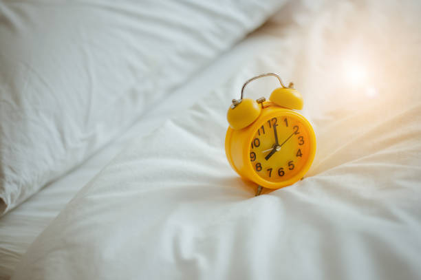 istock Closeup alarm clock  in bed after waking up, sunlight in morning. 1085974034