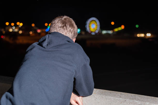 istock Teenager leaning over highway overpass at night. 1085974374