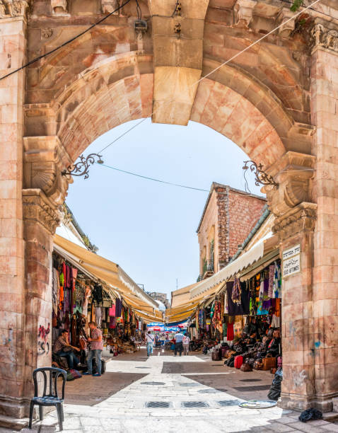 ingresso ad arco in uno dei tanti vicoli dell'antico mercato della città vecchia di gerusalemme pieno di negozi con tutti i tipi di prodotti turistici - arch top foto e immagini stock