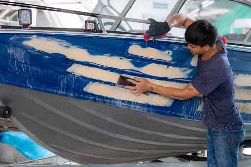 Repairing boat body by puttying close up work after the accident by working sanding primer before painting. , The mechanic repair the boat  , Using plastic putty ,Prepare surface for boat,