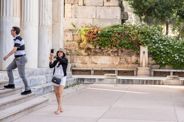 Athens, Greece - October 20, 2018: A stylish woman takes a selfie while visiting the Stoa of Attalos in the Ancient Agora, a beautiful landmark with ruins located near the Acropolis.