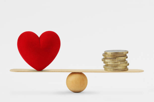 Heart and money on balance scale - Order of priority in life among love and money stock photo