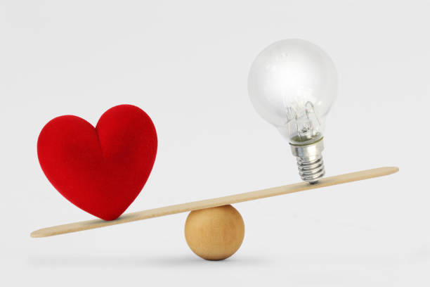 heart and light bulb on scale - concept of love priority over brain in life - sensibility imagens e fotografias de stock