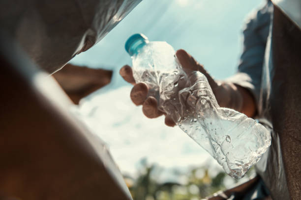 istock hand putting empty plastic bottle in to garbage black bag 1086009824