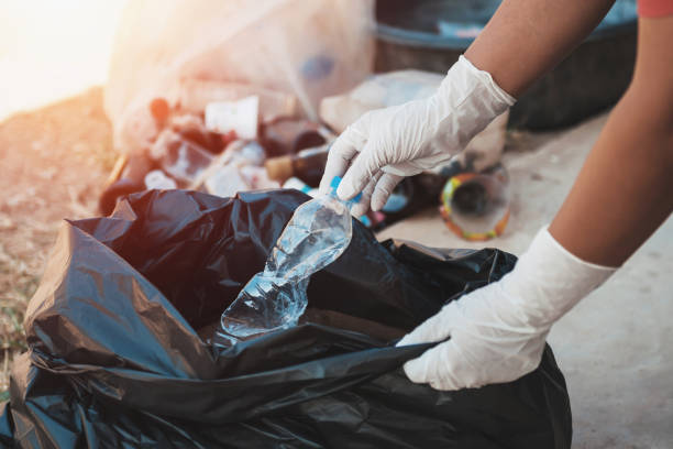 istock hand putting empty plastic bottle in to garbage black bag 1086009826