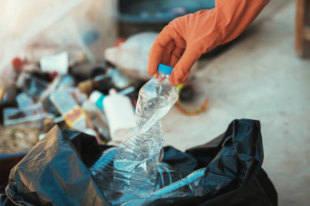 istock hand putting empty plastic bottle in to garbage black bag 1086009832