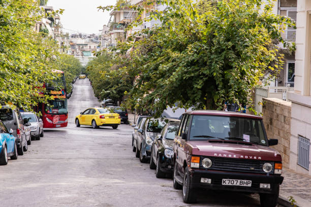 Tour bus in traffic in the Plaka neighborhood in Athens, Greece Athens, Greece - October 20, 2018: A taxi and bus cross paths on a narrow, tree lined street in the historic neighborhood of Plaka, known for its charming architecture and many tourist attractions. city street street corner tree stock pictures, royalty-free photos & images