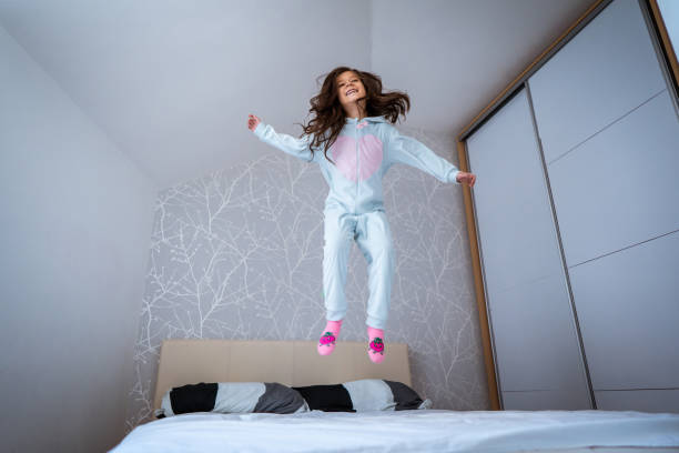 istock Playful girl jumping on the bed 1086027322