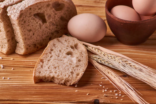 istock fresh delicious bread, concept for baking. Eggs in clay bowl and wheat sprouts on wooden table 1086041578