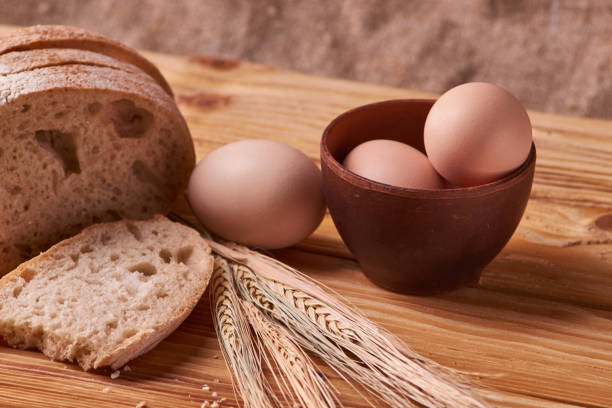 istock fresh delicious bread, concept for baking. Eggs in clay bowl and wheat sprouts on wooden table. concept home teste 1086044170
