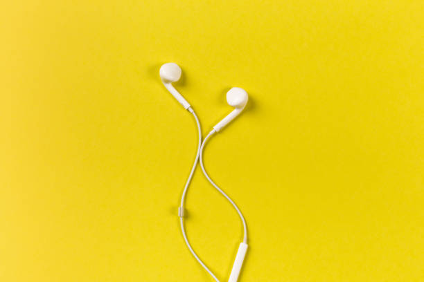 istock White earphones on yellow background 1086051622